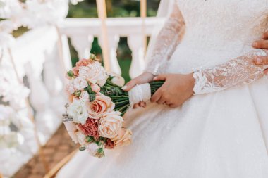 Gelinin bir buketli portresi. Genç ve güzel bir gelin elinde bir buket düğün çiçeği tutuyor. Dantelli gelinlik