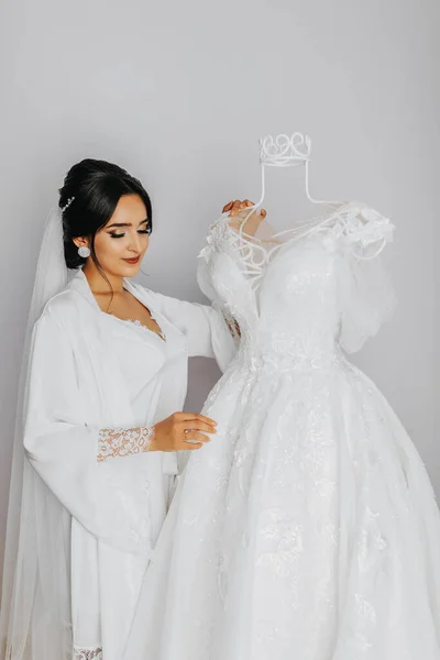 一个穿着晨衣的女孩的画像 快乐的新娘 有着专业的妆容和长长的面纱为摄影师摆设 新娘正在准备婚礼 — 图库照片
