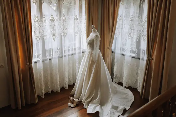 窓からの自然光に照らされたホテルの高価な内装の豪華なレースウェディングドレス — ストック写真
