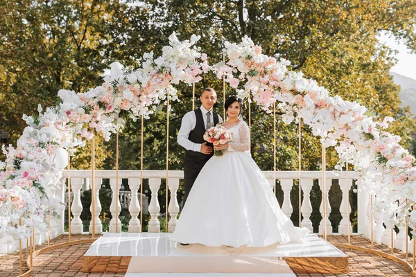 결혼식에서 신부와 결혼식 아치는 꽃으로 장식되어 있습니다 — 스톡 사진