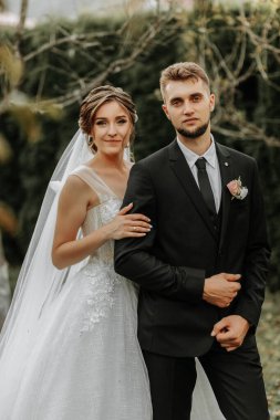 Gelin ve damadın romantik portresi. Bahçede, gelinlik içinde.