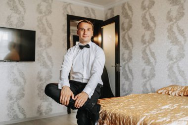 Gelin ve damadın sabahı için hazırlık. Düğün kutlaması için giyinen zarif bir adamın portresi. Damat, beyaz gömlek ve papyon giymiş.