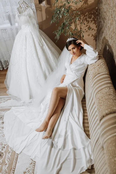 Romantic atmosphere of the bride\'s morning. Bride in a home. Bride morning preparation. Bride in beautiful dress near the mannequin with dress indoors at home. Enjoy every moment