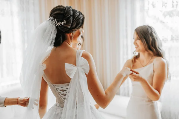 the bride\'s friend prepares the bride for the wedding day. Bridesmaids help tie the bride\'s wedding dress before the ceremony.