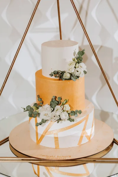A delicious wedding. three-tiered cake decorated with flowers. Candy bar for a banquet. Celebration concept. Fashionable desserts. Table with sweets, candies. Fruits