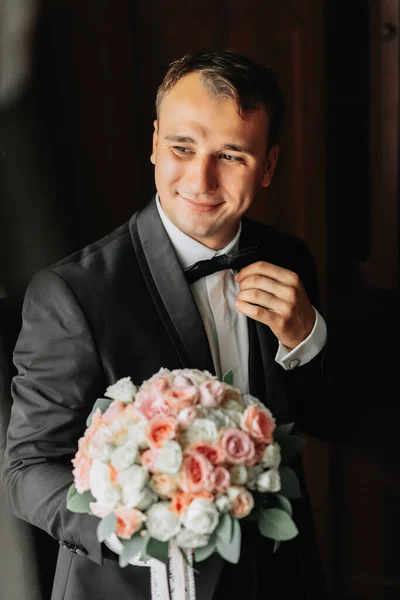 Preparation for the morning of the bride and groom. portrait photo of an elegant man getting dressed for a wedding celebration. The groom, dressed in a white shirt, bow tie and jacket