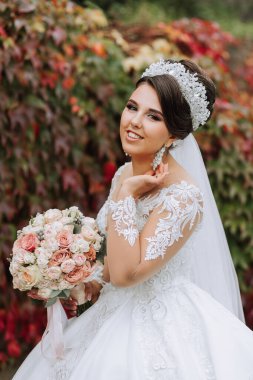 Gelinin sonbahar ormanındaki portresi, düğün töreni, ön manzara. Gelin, sarı sonbahar yapraklarının arka planında