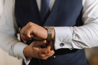 Ellerinde bir erkek saati. Bir adam ayarlar ve bileğine bir saat takar. Damat düğüne hazırlanıyor.