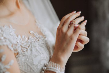 Gelin elinde altın bir yüzük tutuyor, yakın plan. Gelinin sabahı. Düğün günü. Güzel dantel elbise. Seksi kız.