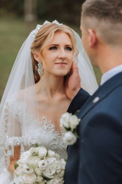 Ormanda ya da parkta şefkatle kucaklaşan zarif bir çiftin portresi. Lüks gelin ve damat kucaklaşması. Romantik şehvetli an