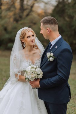 Ormanda ya da parkta şefkatle kucaklaşan zarif bir çiftin portresi. Lüks gelin ve damat kucaklaşması. Romantik şehvetli an