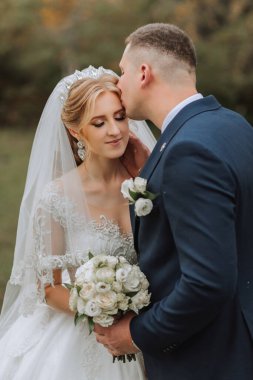 Ormanda ya da parkta şefkatle kucaklaşan zarif bir çiftin portresi. Lüks gelin ve damat kucaklaşması. Romantik şehvetli an