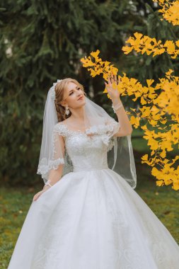 Güzel gülümseyen bir gelinin portresi. Gelinin sonbahar portresi. Sarı sonbahar yaprakları