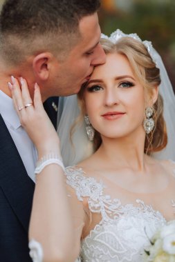 Ormanda ya da parkta şefkatle kucaklaşan zarif bir çiftin portresi. Lüks gelin ve damat kucaklaşması. Romantik şehvetli an