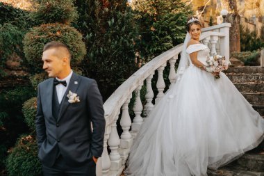 Mutlu düğün çifti portresi, sonbahar ormanında gelin ve damat taş merdivenlerin yanında poz veriyor. Takım elbiseli bir adam, gelinlikli bir kız.