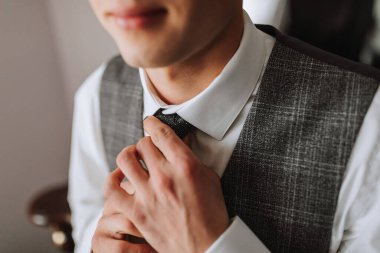 Şık bir genç adam takım elbise ve kravat takıyor. İş stili. Modaya uygun bir görüntü. Damat düğün için hazırlanıyor. Seksi bir adam. Eller yukarı.