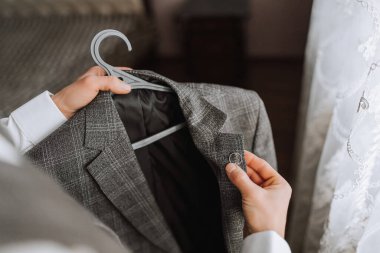 Adam ceketini askıda tutuyordu. Damat düğün töreni için hazırlanıyor. Ellerin detaylı yakın plan fotoğrafı.