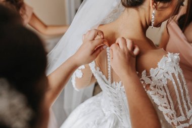 Close-up photo of a beautiful bride from the back, bridesmaids helping to tie the wedding dress clipart