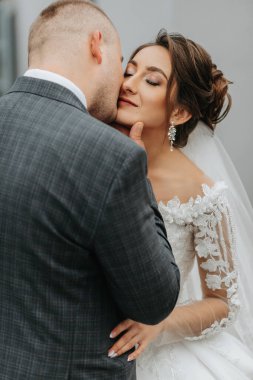 Şık gelin ve damat nazikçe sarılıp öpüşüyor. Güz parkında modern buketli, şık damadı kucaklayan güzel gelin. Duygusal romantik an. Düğün için. Şık ve güzel..