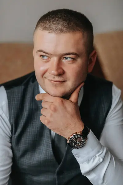 Portrait of a man with a stylish watch in a business suit. the groom is preparing for the ceremony. Friends help the groom prepare for the wedding. The man puts on a suit and prepares for the meeting