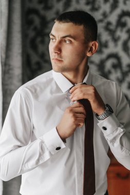 Damat odasında kravatını takar ve düğün için hazırlanır. Adam kravat takıyor.