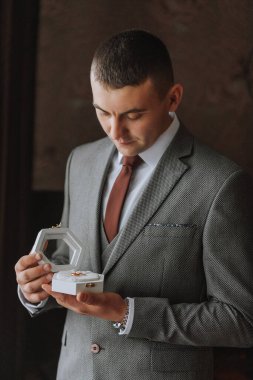 Altın alyanslar hediye kutusunda, damadın elinde, yakın plan.