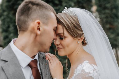 Şık gelin ve damat nazikçe sarılıp öpüşüyor. Güz parkında modern buketli, şık damadı kucaklayan güzel gelin. Duygusal romantik an. Düğün için. Şık ve güzel..