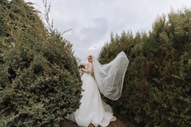 Şehvetli bir gelinlik ve profesyonel makyajla uçan duvağı olan güzel bir gelinin portresi. Genç ve güzel bir gelinin yakın plan portresi. Düğün..