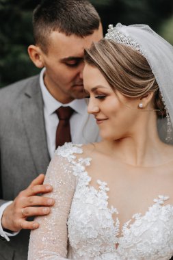 Şık gelin ve damat nazikçe sarılıp öpüşüyor. Güz parkında modern buketli, şık damadı kucaklayan güzel gelin. Duygusal romantik an. Düğün için. Şık ve güzel..