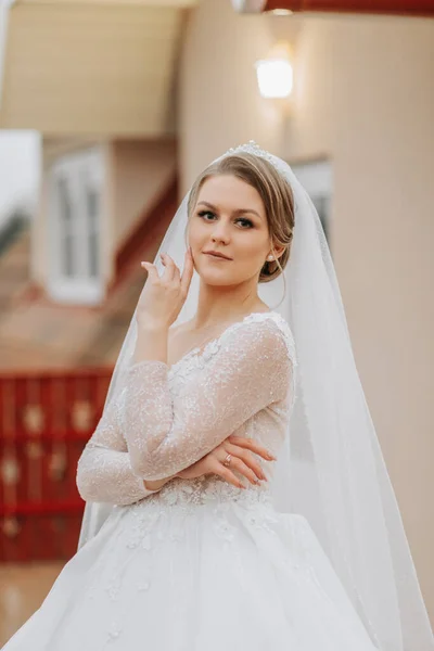 Portrait of a beautiful bride with a flying veil in a voluminous wedding dress and professional make-up. Close-up portrait of a young gorgeous bride. Wedding.