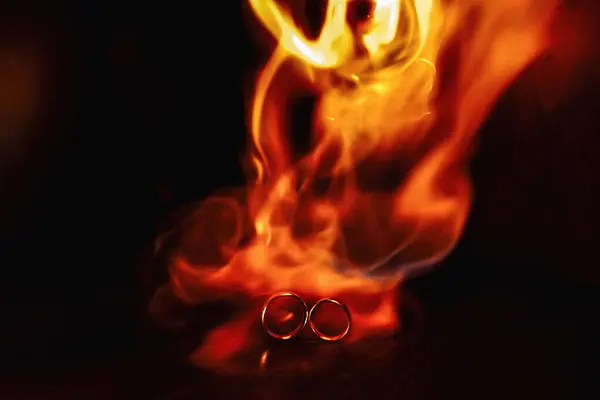 two wedding rings in the flames of fire. Wedding. Traditions. Fiery flame on a dark background