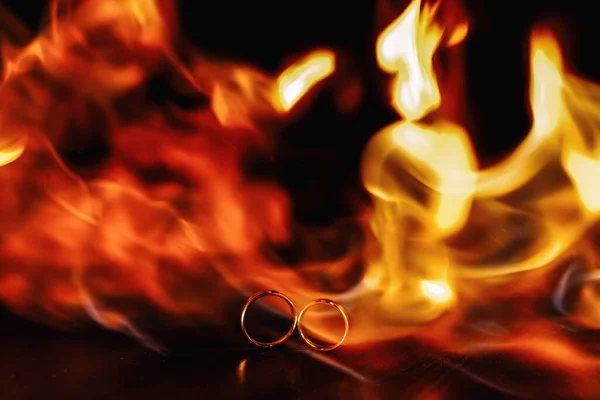 two wedding rings in a flame of fire on a dark background. Wedding. Traditions. Fire element