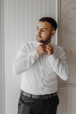 Neşeli bir çift genç gelin otel odasında sarılıp öpüşüyor. Gelinlik giymiş gelin, güler yüzlü damadı klasik resmi kıyafetlerle omzundan kucaklıyor. Gelin ve damadın ilk buluşması.