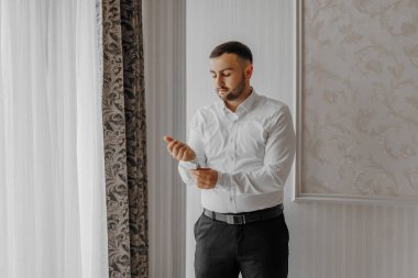 Neşeli bir çift genç gelin otel odasında sarılıp öpüşüyor. Gelinlik giymiş gelin, güler yüzlü damadı klasik resmi kıyafetlerle omzundan kucaklıyor. Gelin ve damadın ilk buluşması.