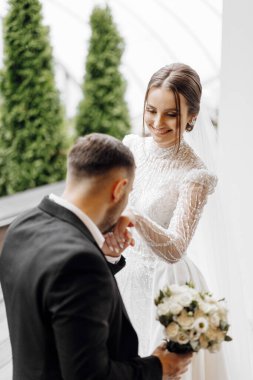 Damat geline nazikçe dokunur, gelin ve damada yürür. Güzel gelin. Yeni yaratılmış düğün ailesi. Damat gelinin elini öpüyor. Aşık güzel bir çift.