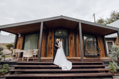 Şirin yeni evliler restoranın yakınında nazikçe sarılıp gülümsüyorlar. Gelin ve damadın dantel bir elbise içindeki portresi..