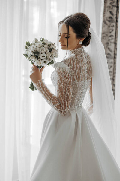 fashion portrait of a beautiful bride in a luxurious wedding dress with lace and crystals in an Arabic interior style. Beautiful bride with a bouquet of flowers. Preparation for the wedding ceremony.