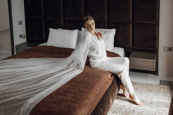 Krásná Sebevědomá Nevěsta Sedící Bílém Pyžamu Dlouhým Závojem Hotelovém Pokoji — Stock fotografie