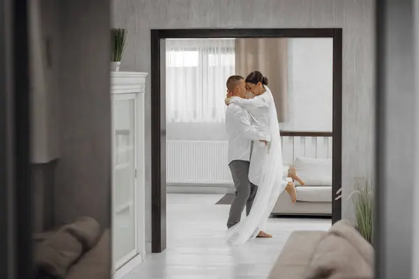 Happy bride and groom in a hotel room in the morning. Brides in love. A confident girl is a bride in the arms of the groom. Preparation for the wedding.