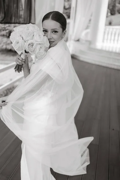 portrait of the bride in a wedding dress with a bouquet of flowers in her hands. Black and white photo