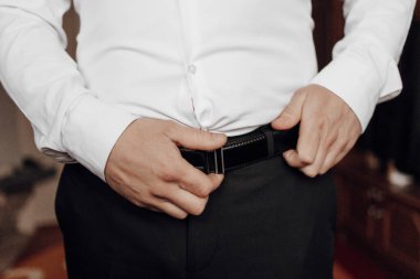 Ellerinde bir erkek kemerinin fotoğrafı. Kesilmiş ve bulanık fotoğraf. Erkek tarzı. İş için. Moda.