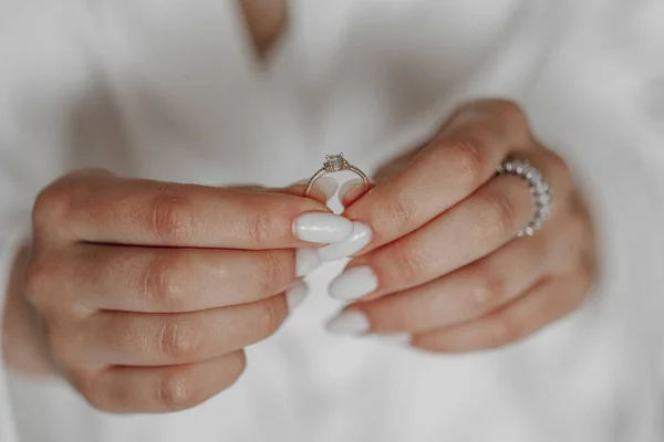 the bride holds a diamond engagement ring. Beautiful hands of the bride.