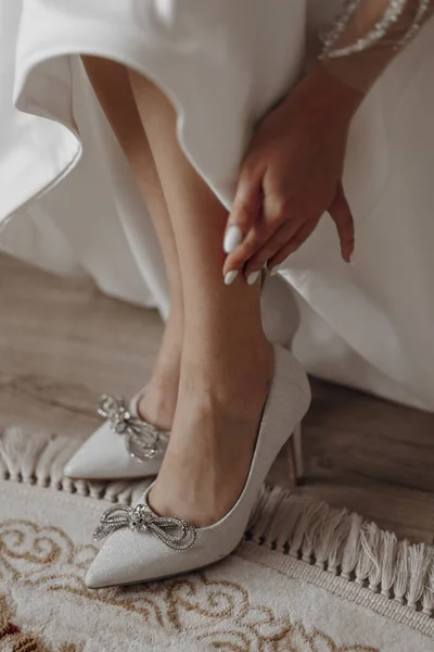 The bride in a wedding dress puts shoes on her feet