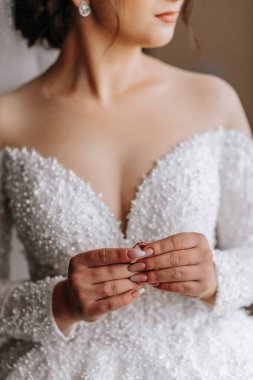 Gelin elinde bir alyans tutuyor. Gelinin güzel elleri. Omuzlarını aç. Düğün detayları.