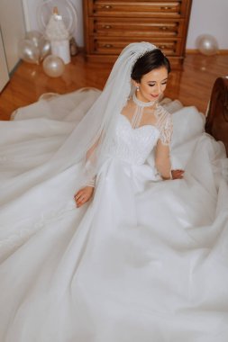 Lüks elbiseli ve peçeli gelin odasında poz veriyor. Gelinin sabahı. Hazırlık. Düğün fotoğrafçılığı