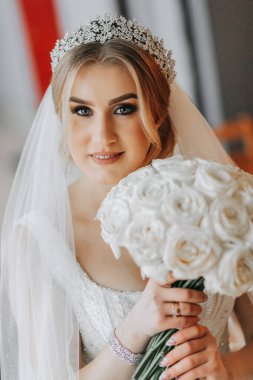 Düğün portresi. Gelin zarif bir elbise, uzun bir peçe, bir buket tutuyor ve bir yürüyüş sırasında kış bahçesinde yürüyor.