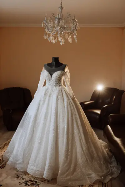 wedding dress in the interior of the bride\'s room. Voluminous wedding dress with sleeves and open shoulders.