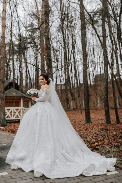 신부는 기차와 볼륨의 드레스를 꽃다발을 숲에서 산책하는 결혼식 — 스톡 사진