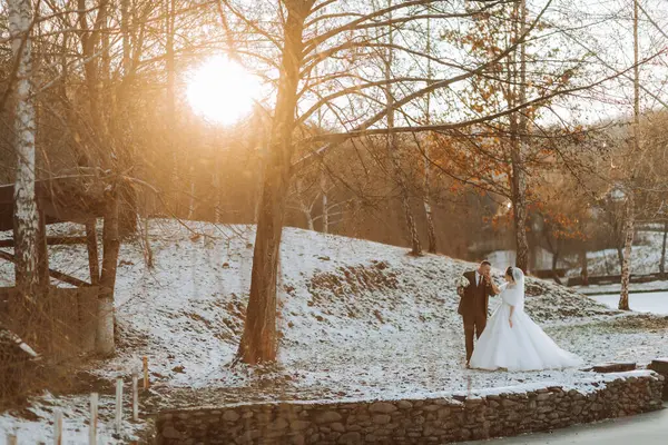 The bride and groom are walking in the winter garden. Winter photo session in nature.