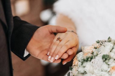 Damat gelinin parmağına yüzük takar. Yüzük değişimi. Mutlu çift kışın dışarıda evleniyor..